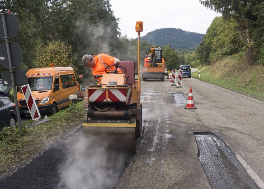 Bitumenemulsio wird mit einer Walze bei einer Straßenreparatur verteilt